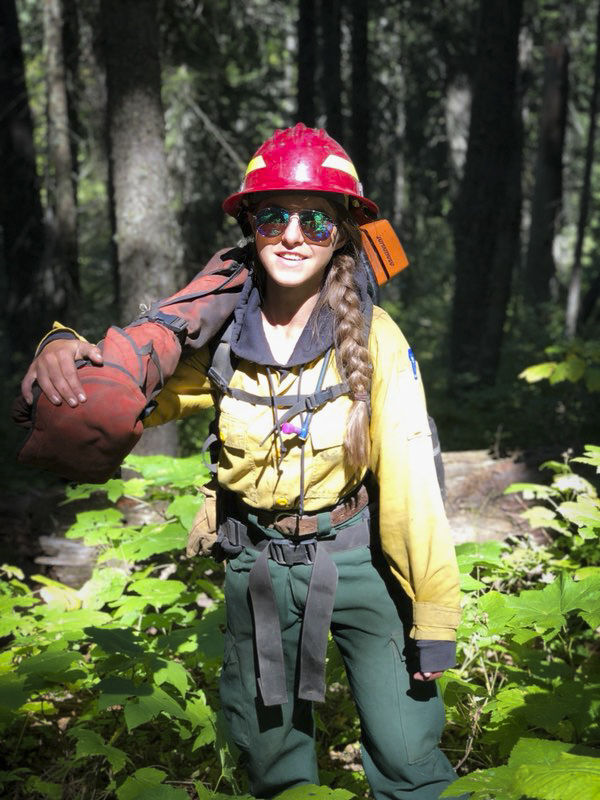Lea Bossler carries a saw on a wildland fire.